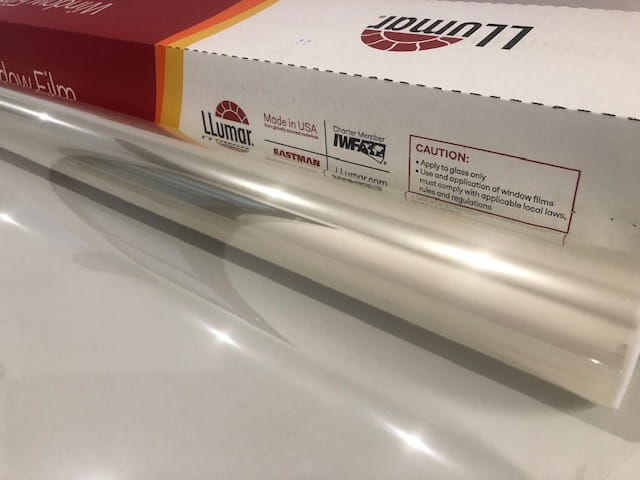 Clear window film roll partly unrolled beside a LLumar branded box