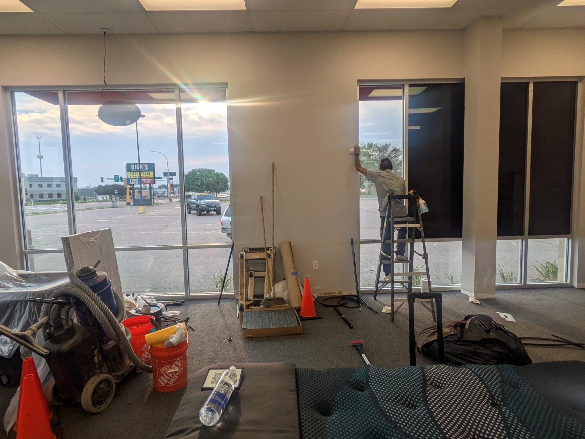 Installer applying window film to large storefront windows of a Sioux City retail space during installation (interior)